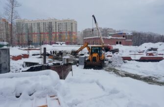 экскаватор чистит снег на строительной площадке